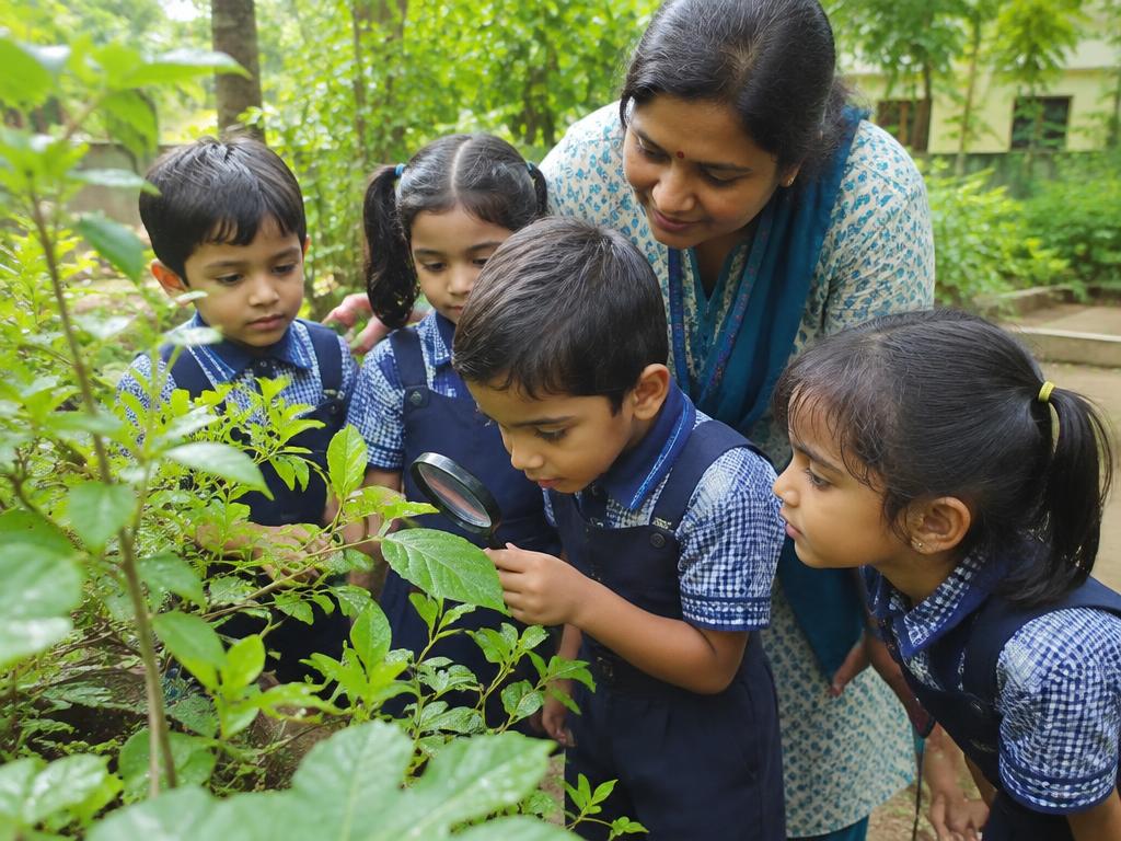 Children looking at leaves through a magnifying glass